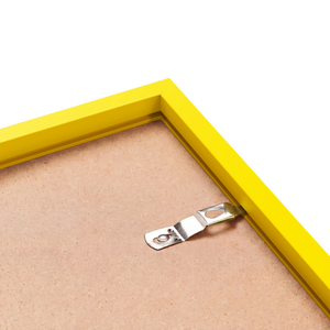 Back corner of a yellow wood picture frame with sawtooth hanger